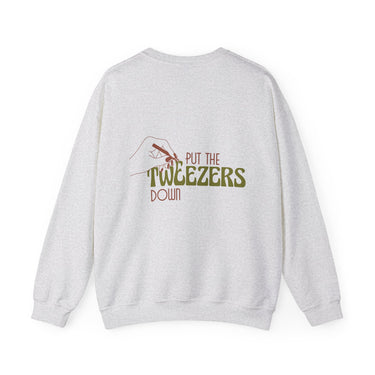 Grey marl sweatshirt featuring a back print of a brown outline hand holding tweezers with the phrase 'PUT THE TWEEZERS DOWN' in brown and bold green text