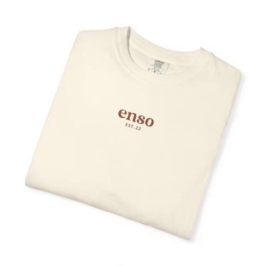 Cream-colored t-shirt, folded and displayed on a white background, featuring brown "enso EST. 22" lettering on the chest and a Comfort Colors brand tag visible inside the collar