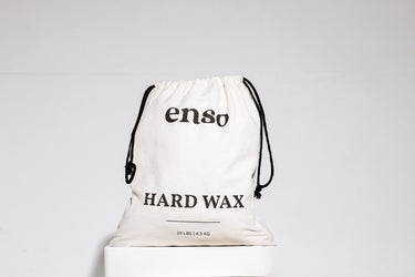 A beige drawstring bag featuring the black enso logo and HARD WAX text with 10 LBS | 4.5 KG weight details displayed on a white studio pedestal