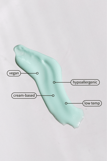 Mint green cosmetic cream swatch on a white background with labels detailing its vegan hypoallergenic and cream-based properties