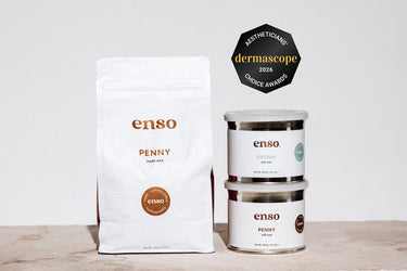 Product photography of Enso's Penny hard wax 1kg bag with "vegan antimicrobial hypoallergenic" label and copper-toned branding, beside stacked 400g tubs of Enso Patina and Penny soft waxes on a light textured surface, all beneath a Dermascope 2026 Aestheticians' Choice Awards badge